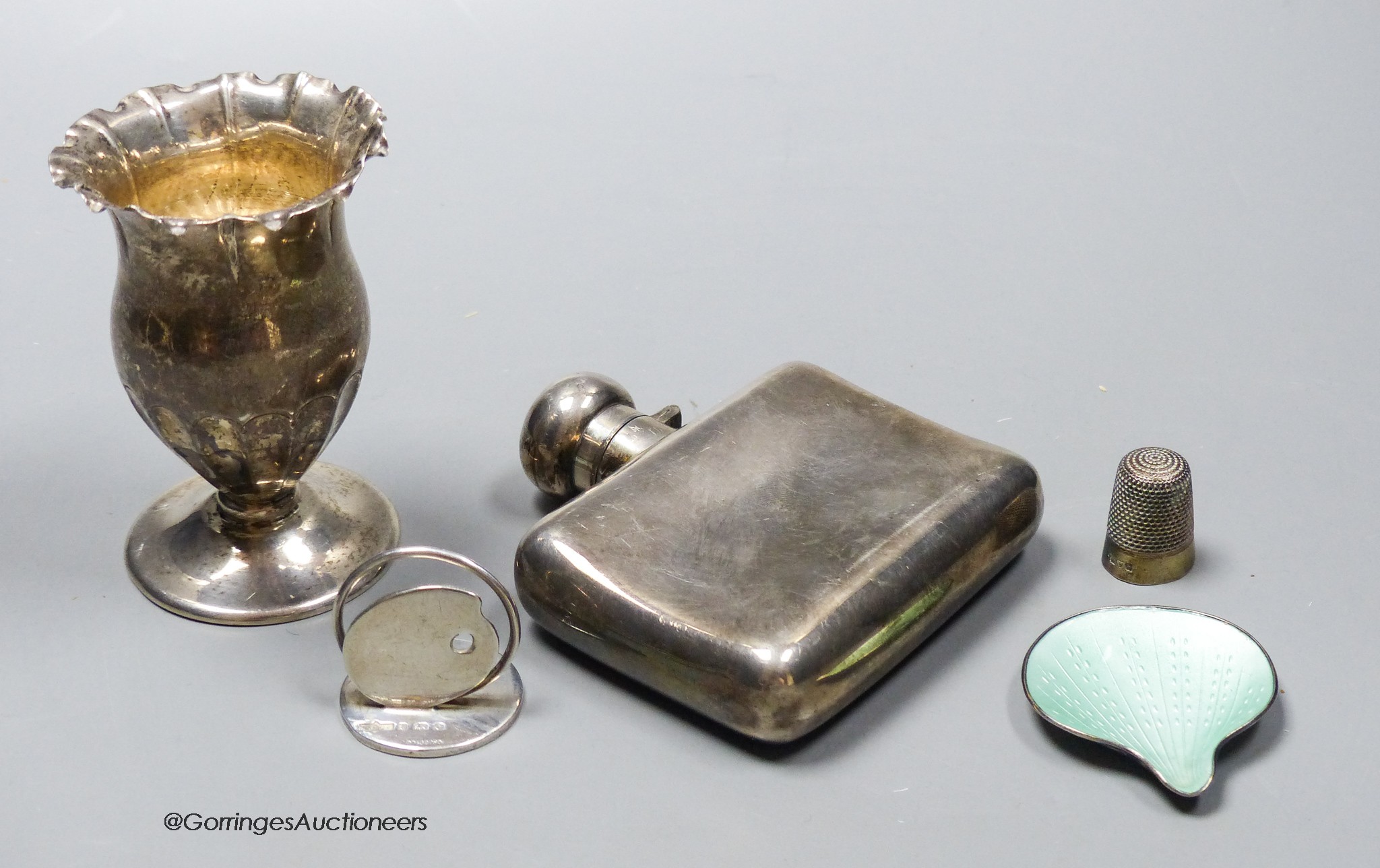 A George V silver hip flask, width 85mm, a small silver vase, a silver menu holder, a silver thimble and a Norwegian sterling and enamel small dish, gross 6oz.